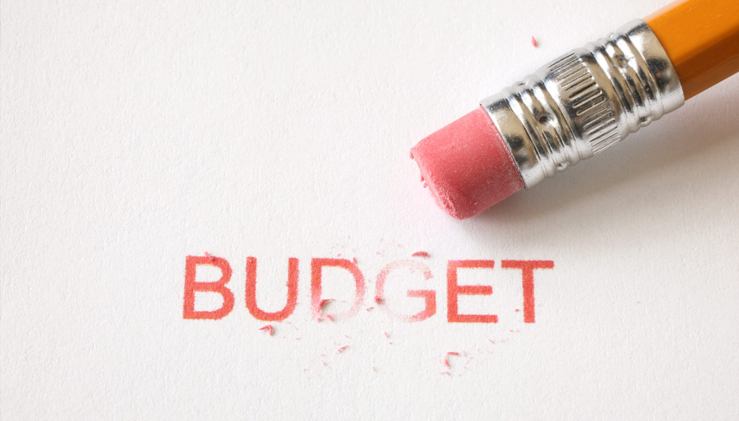 A pencil eraser erasing the word budget on a piece of paper