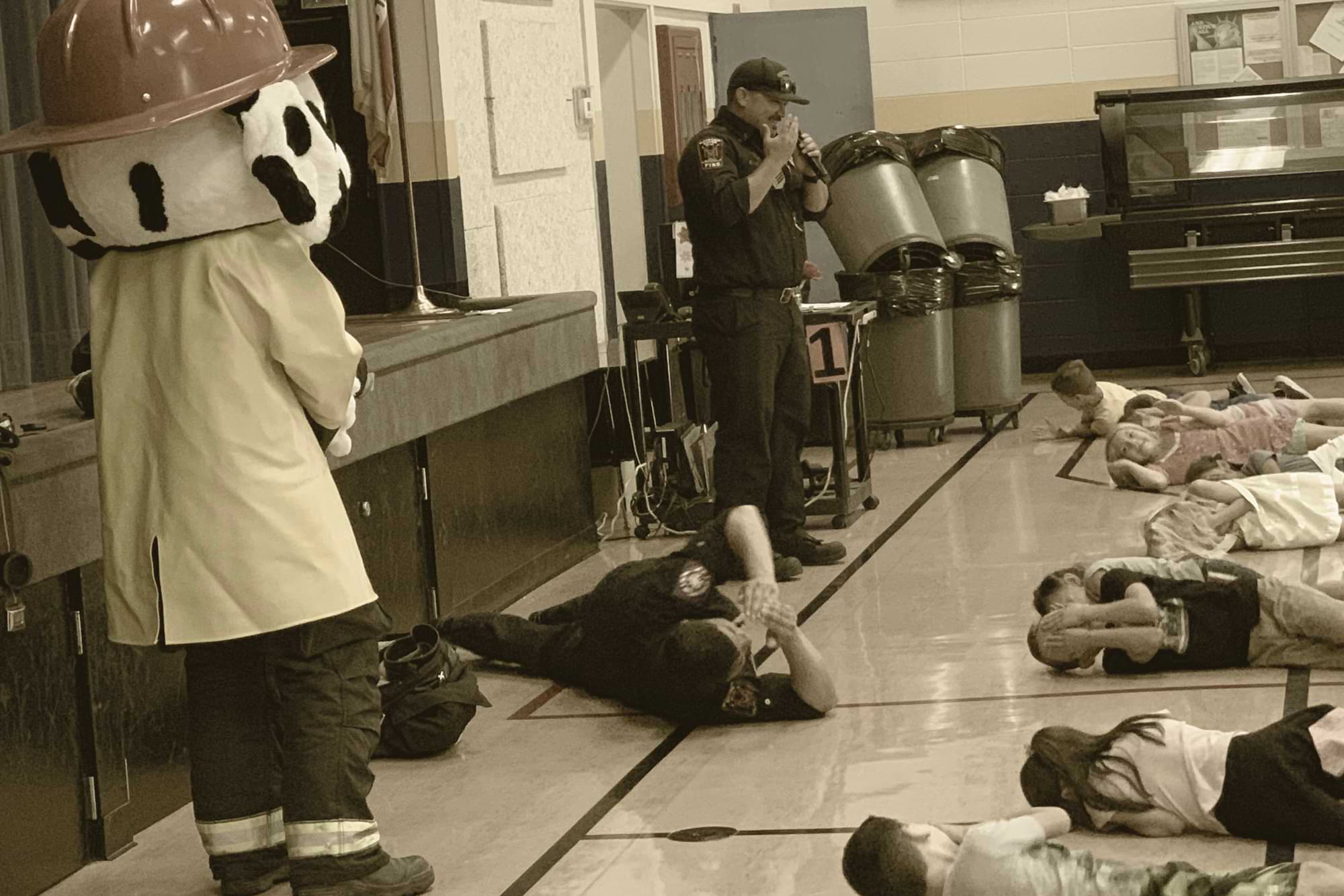 Firefighters teaching students safety drills in school auditorium