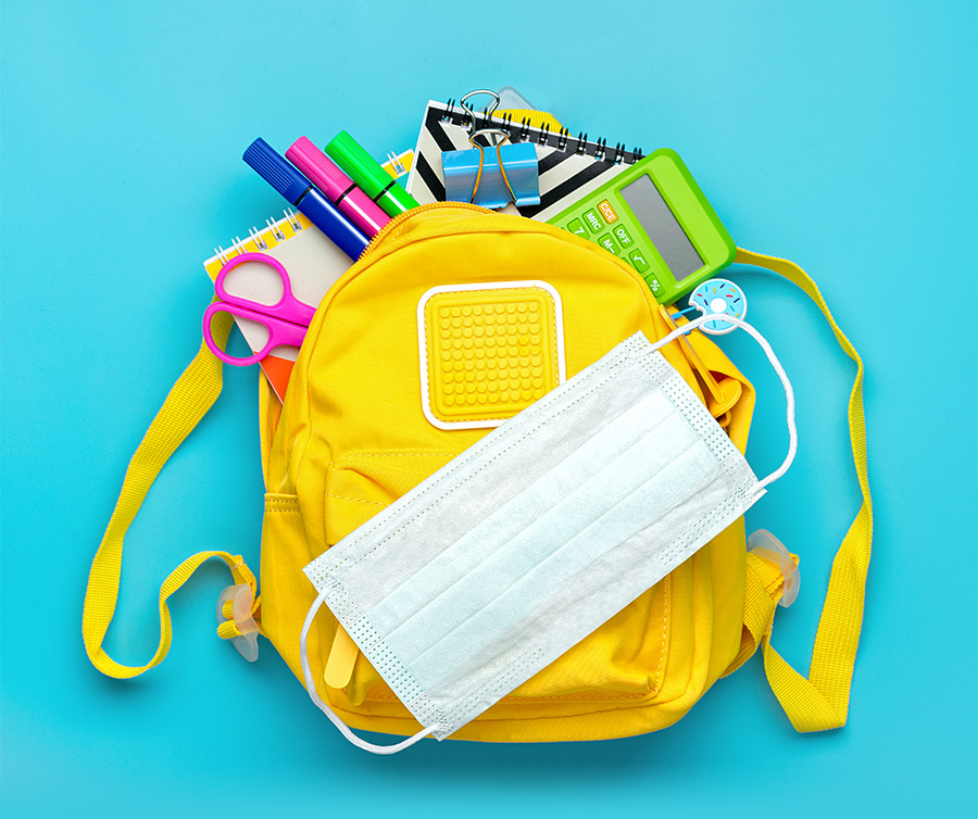 yellow backpack with a mask and school supplies inside