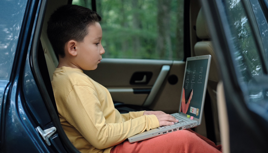 Young boy using laptop in a car