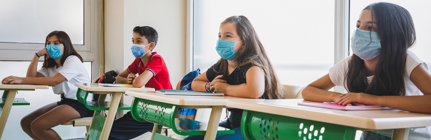 students with mask sit at attention in class