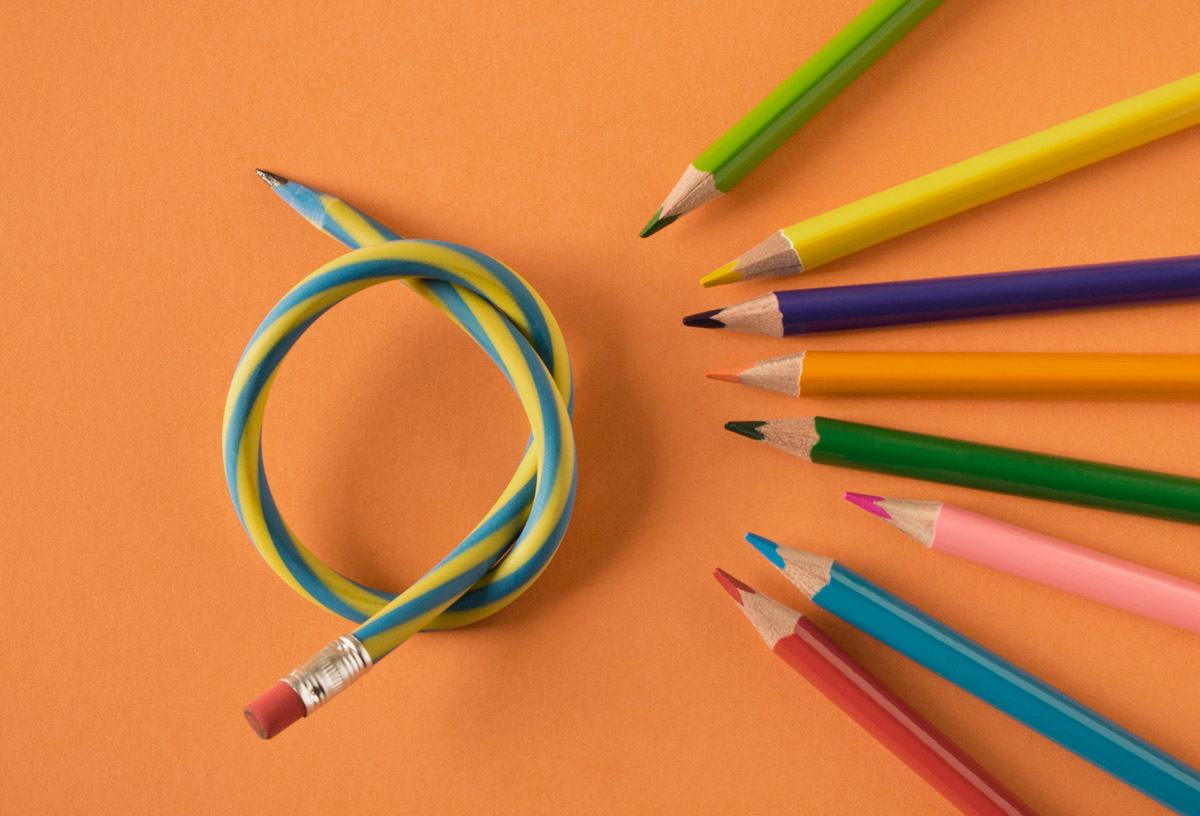 A flexible pencil tied in a knot and surrounded by a group of wooden pencils pointing toward it