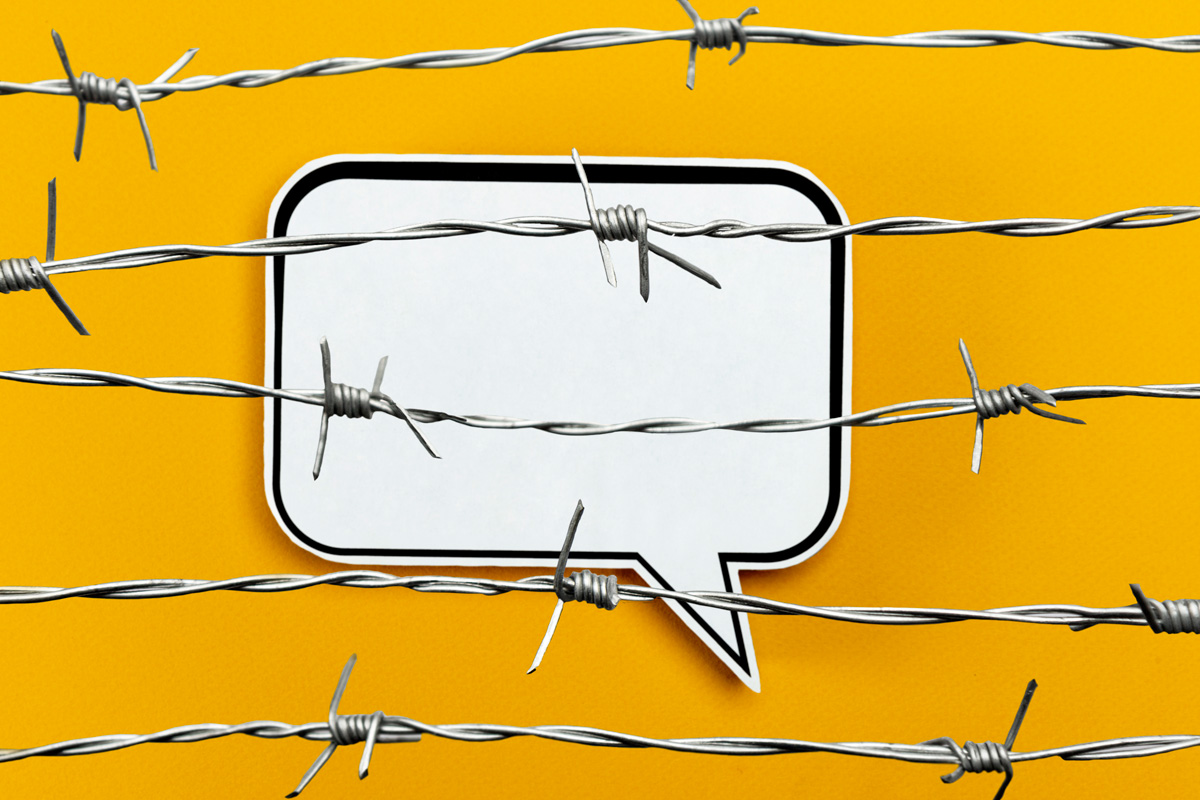 A speech bubble paper cut-out on an orange background behind barbed wire