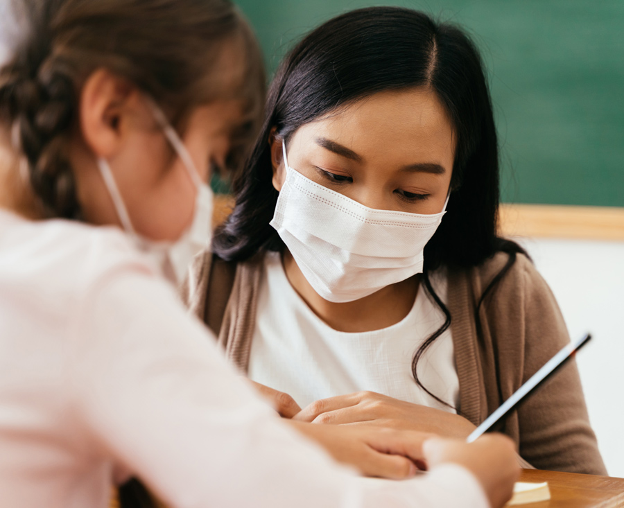 Two students collaborating together in a classroom with masks on