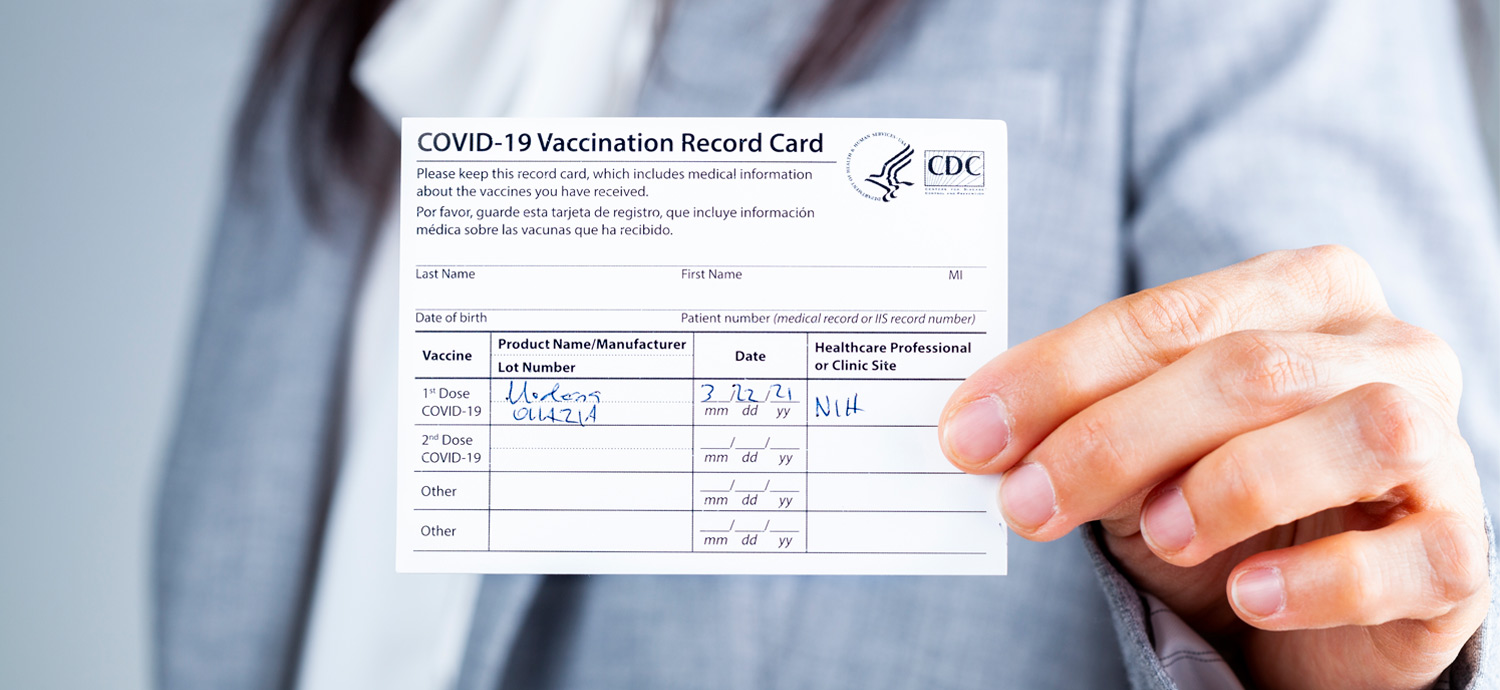 close view of hand holding COVID vaccination card
