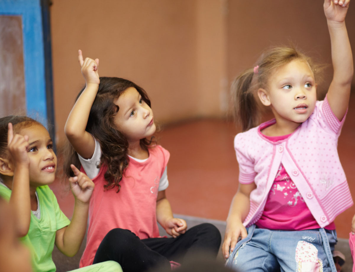 Kids raising their hands to answer question in class