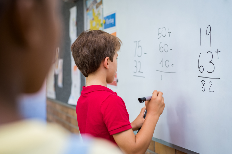 Young boy doing math on a whiteboard
