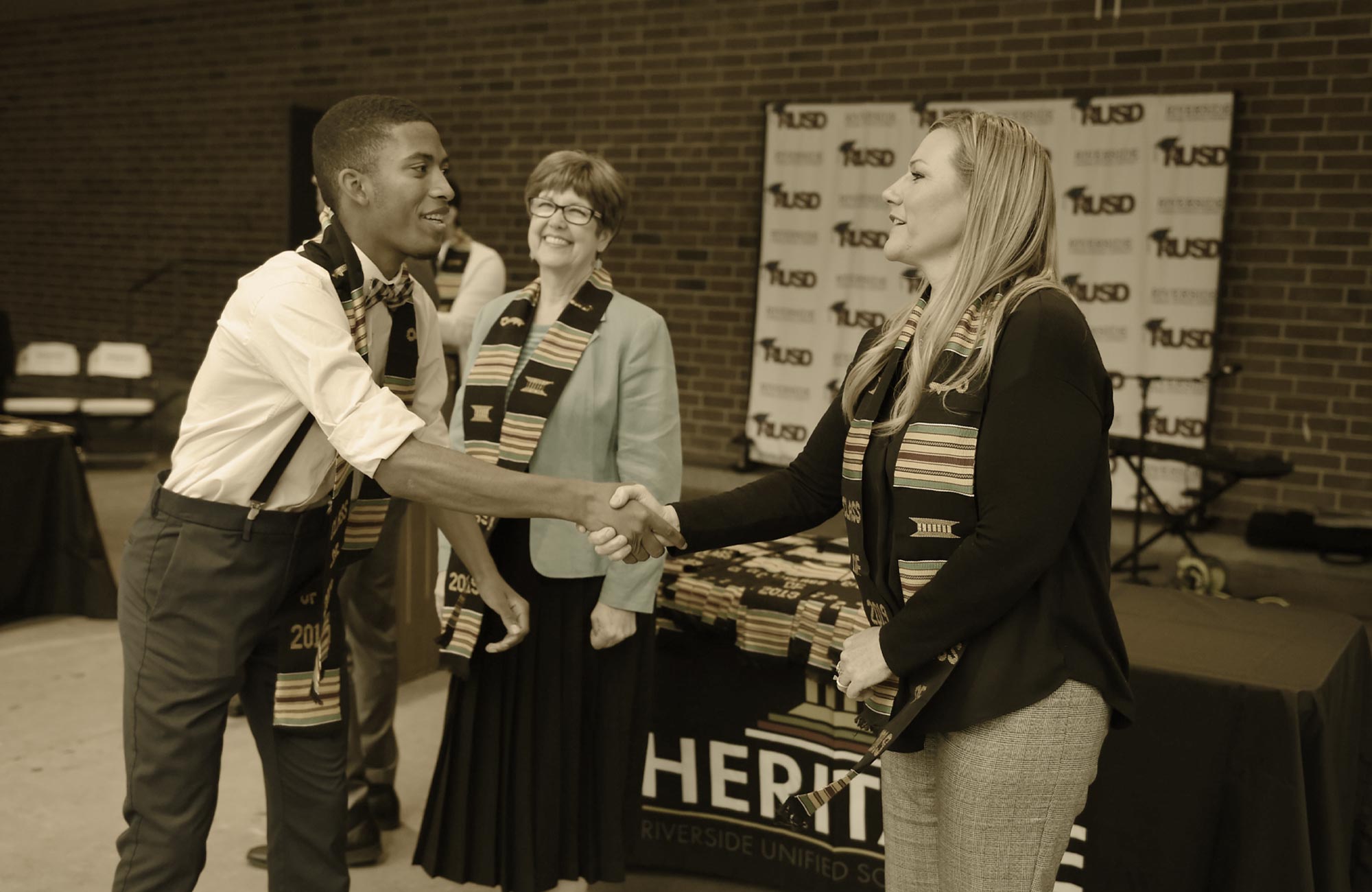 a student and member of faculty shake hands at an event