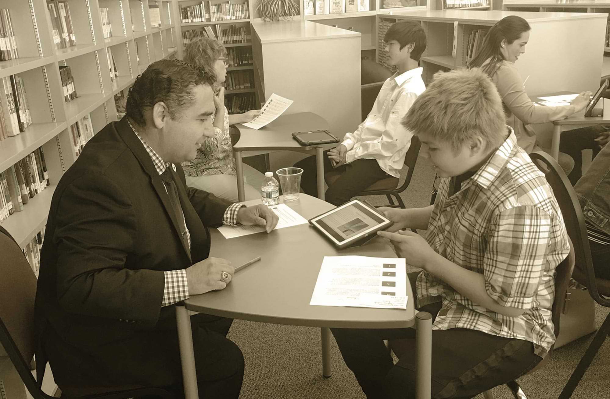 a middle school aged student and an adult tutor work on a iPad together