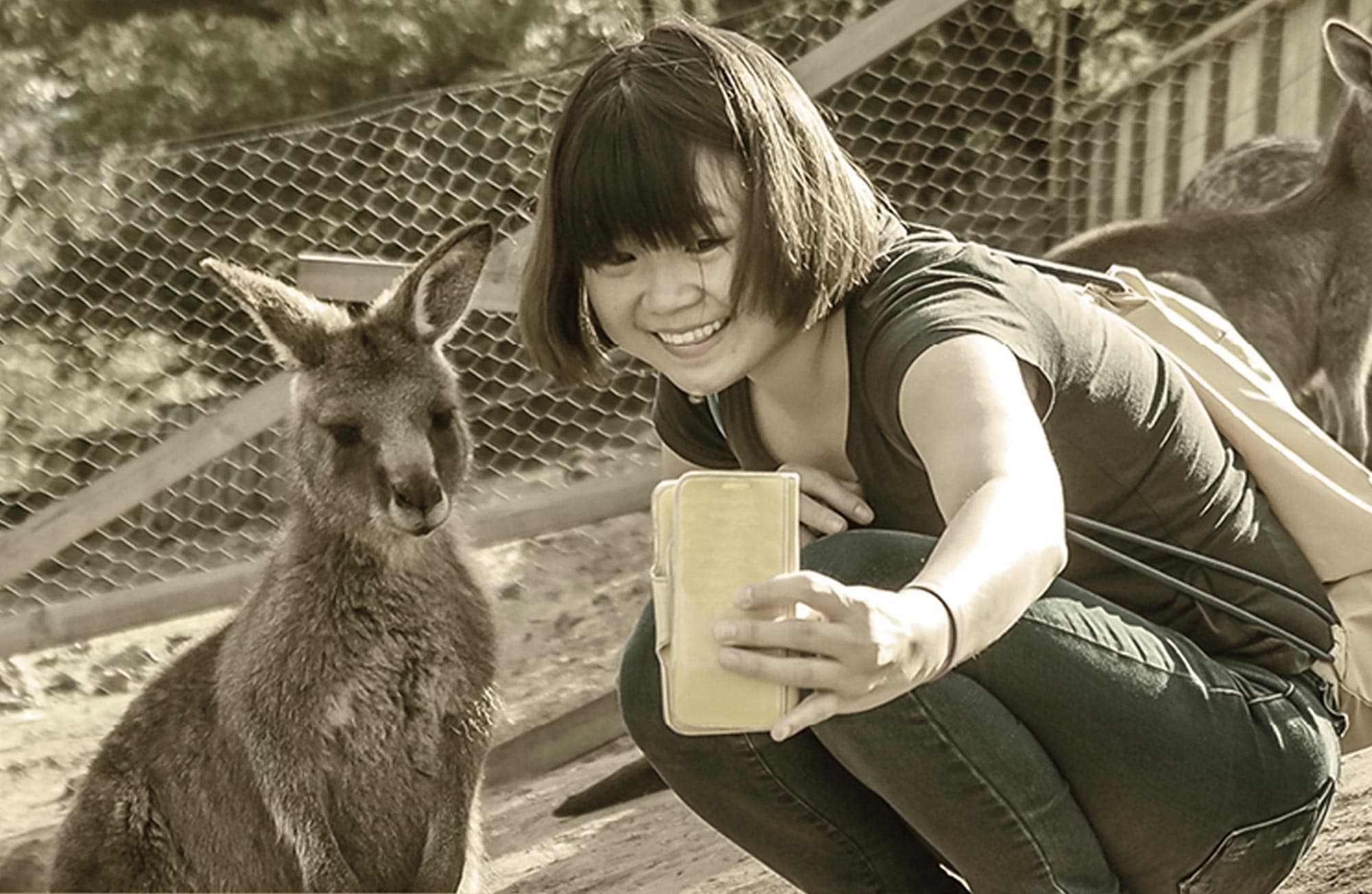 a young woman smiles taking a selfie with a kangaroo