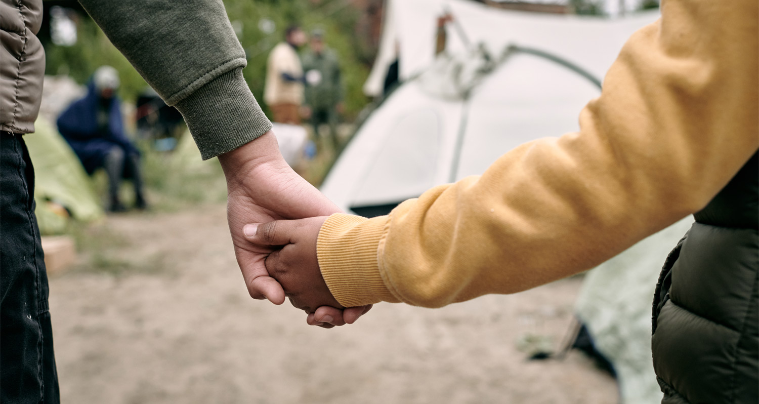 a childs hand being held by an adults hand at an outdoor camping area
