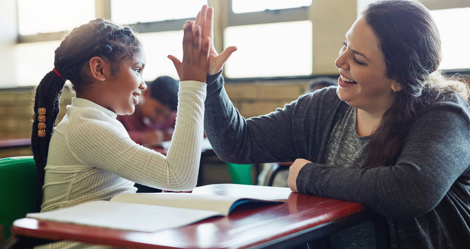 student and teacher high five at desk