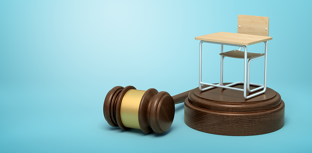 Miniature school desk and chair atop a sound block, next to a gavel