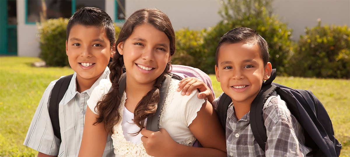 Young Latino students in front yard