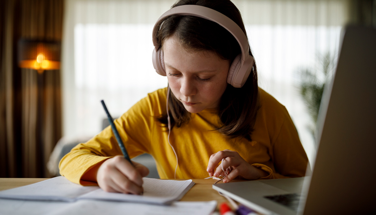 Girl with headphones on doing homework
