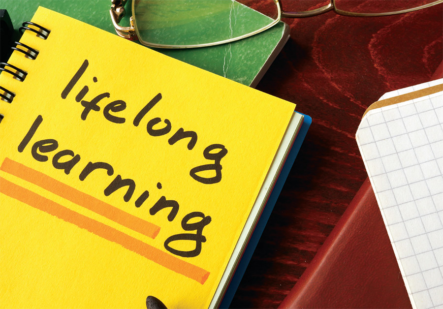 A photograph of three notebooks situated next to each other with the yellow notebook front cover showing the title: lifelong learning