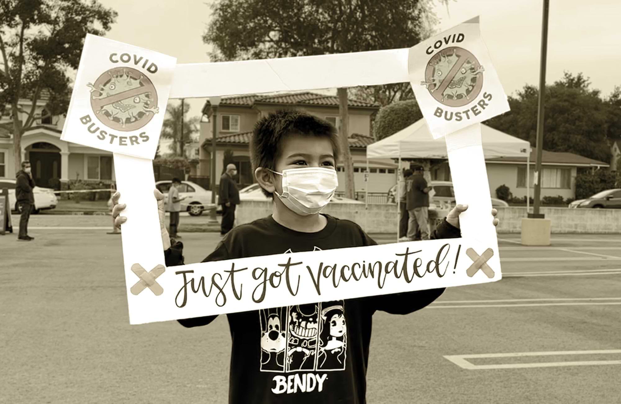 an elementary school aged child holds a frame sign reading "I just got vaccinated"