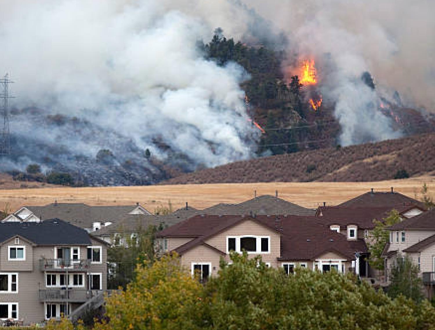 distant view of a fire burning hills behind a neighborhood