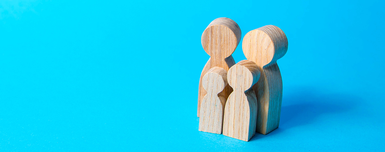 four simplified wooden figures grouped together symbolising a family