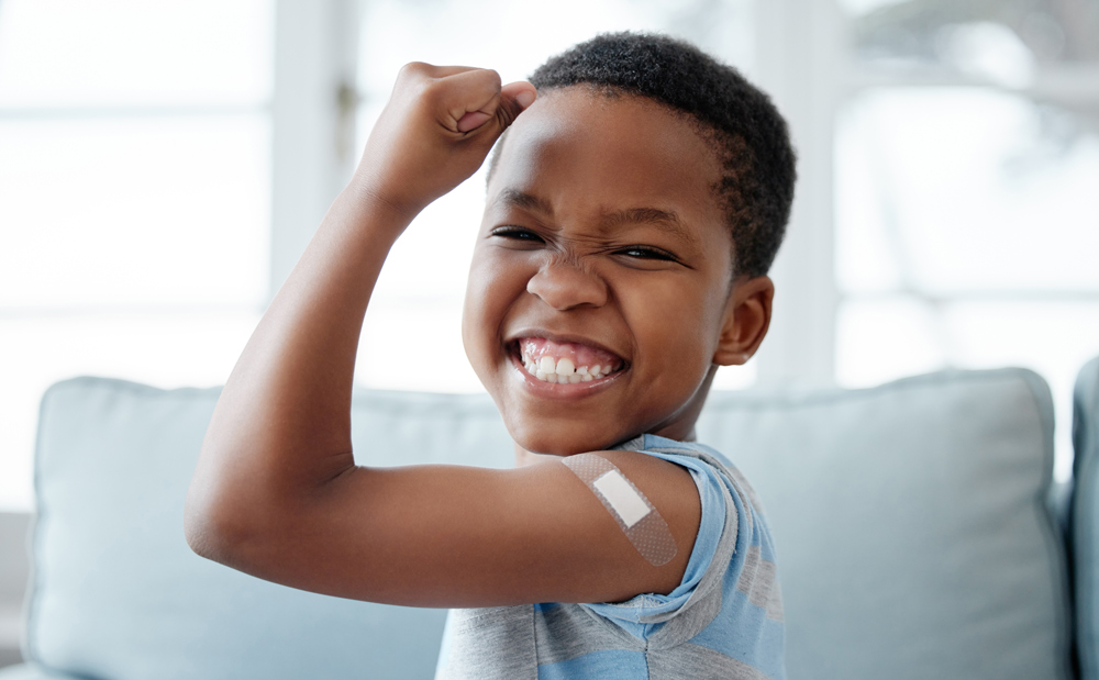 young child flexing arm with bandaid to the camera