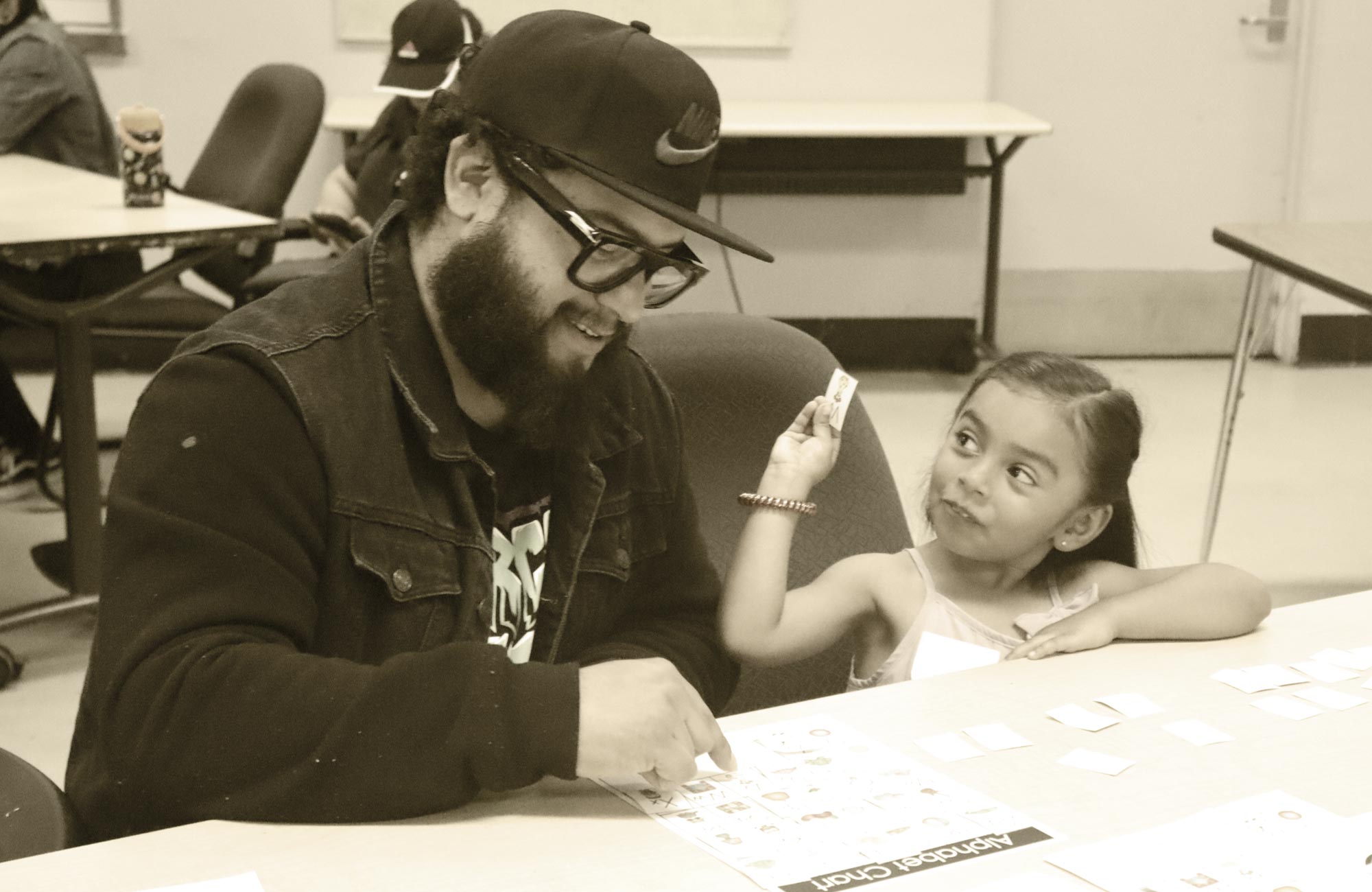 a young girl sits at a table doing work with her adult at an El Monte City School District TK & Kinder Readiness Academy event