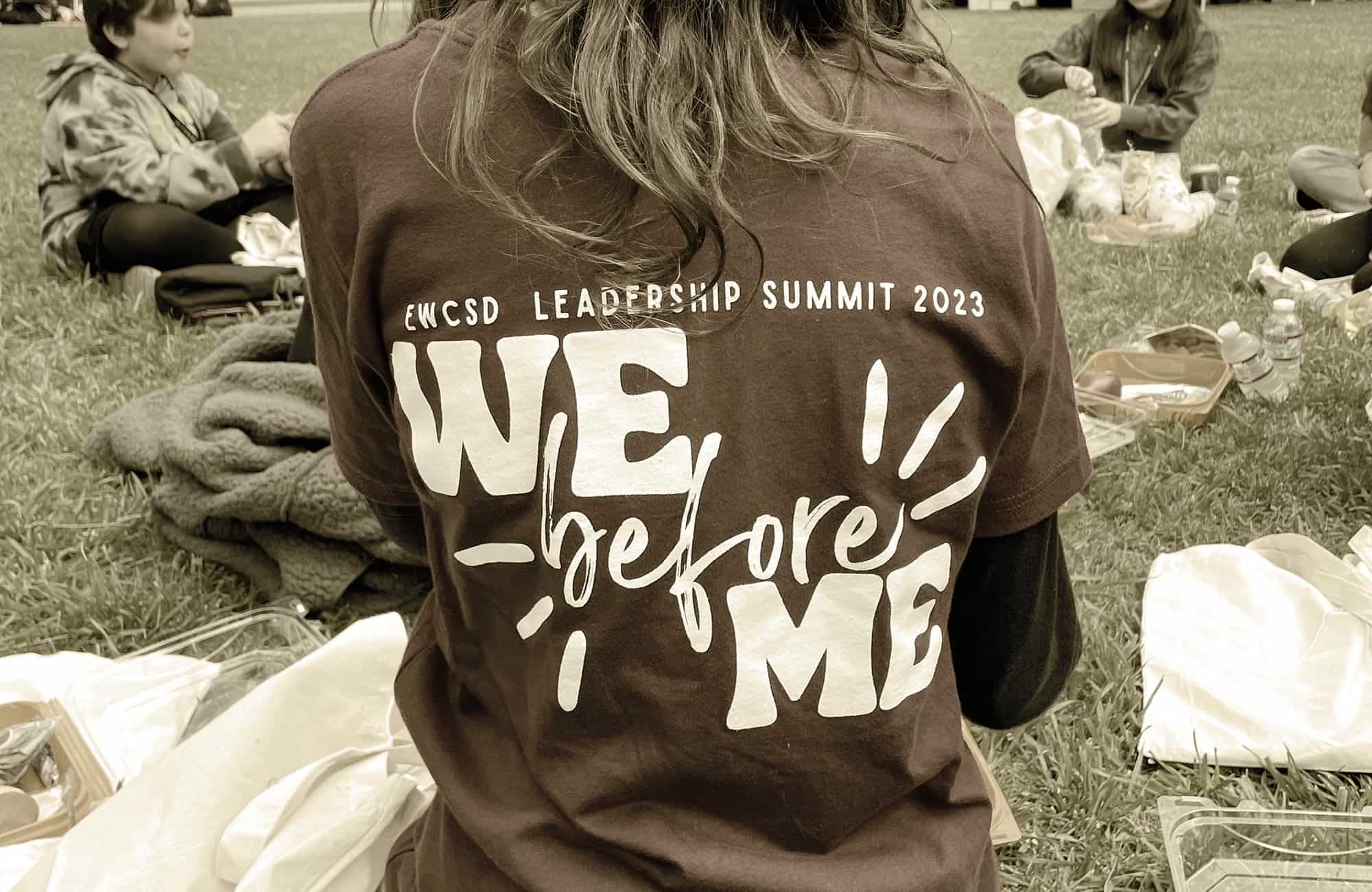 close back view of a person wearing a shirt that reads: EWCSD Leadership Summit 2023 - We before Me