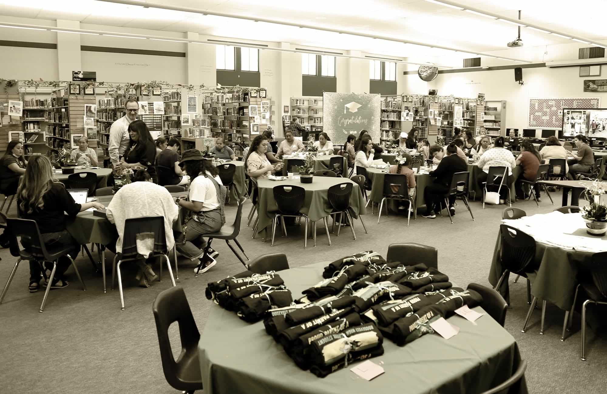attendees sit at tables doing work at a Fresno Unified School District Parent University meeting held in a campus library