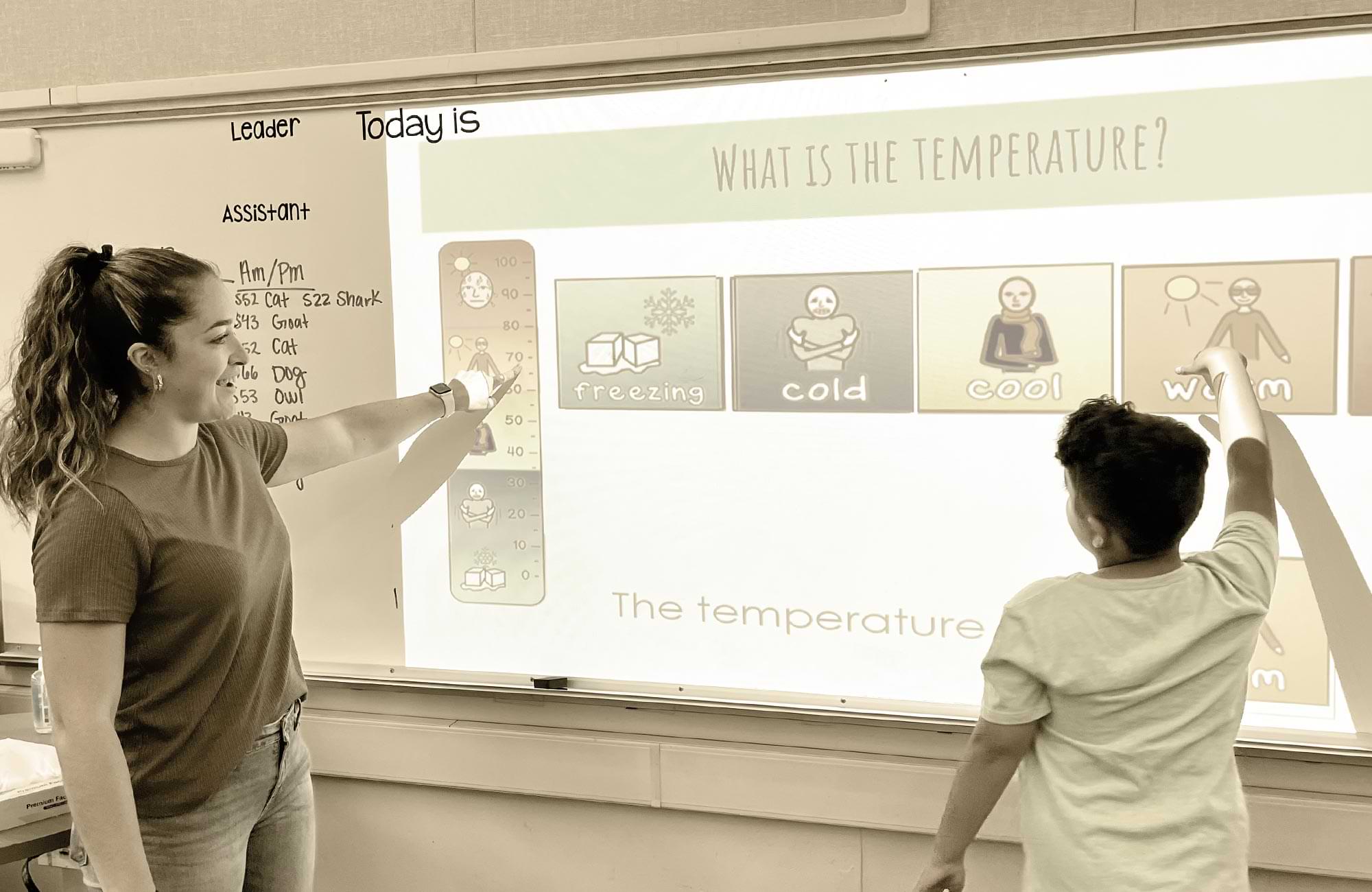 a Clovis Unified School District teacher stands at a whiteboard with an elementary student, using a projector they do a weather/temperature exercise