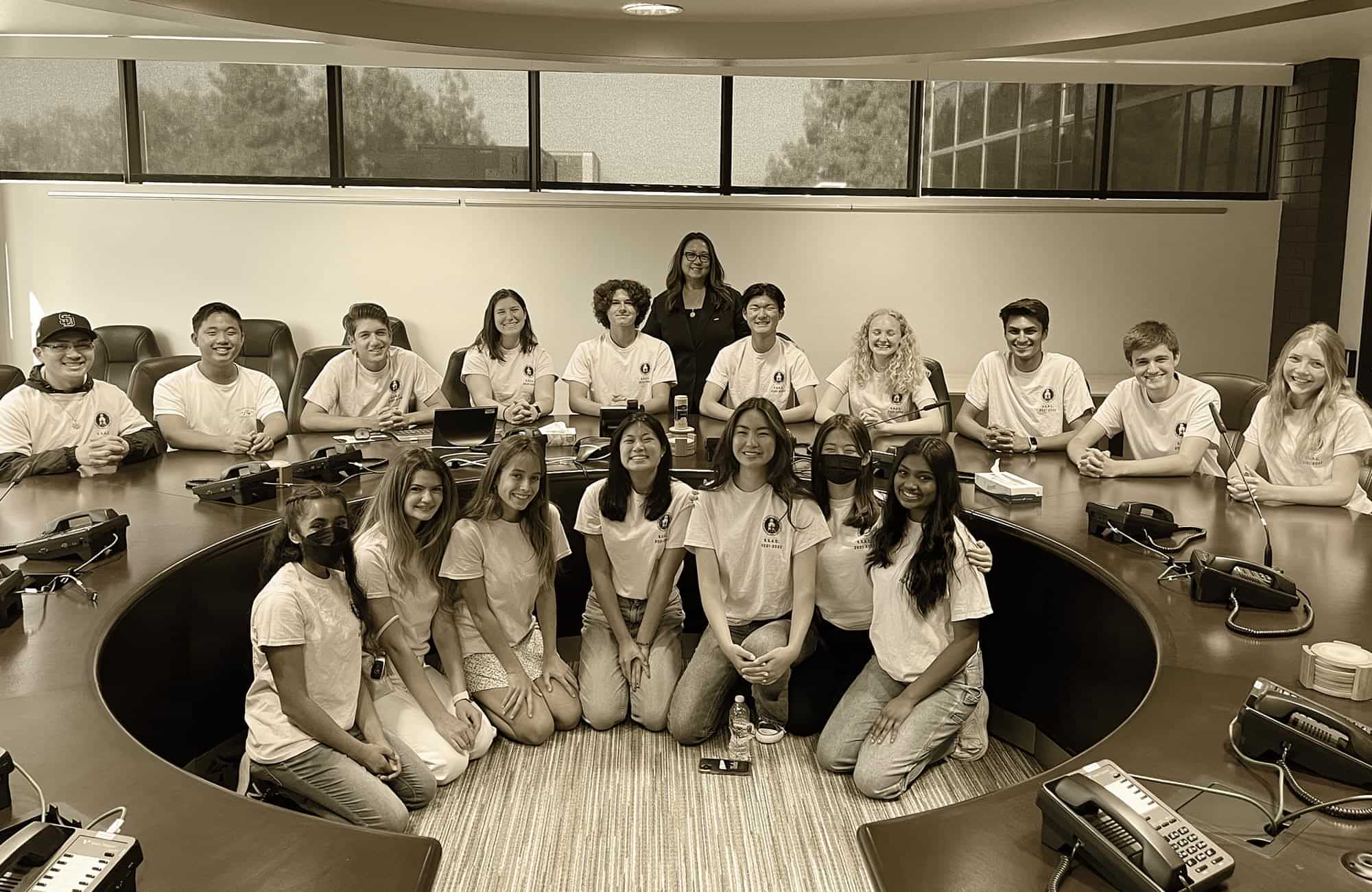 the Poway USD Superintendent’s Student Advisory Council (SSAC) taking a large group photo in a conference room with a large circular desk