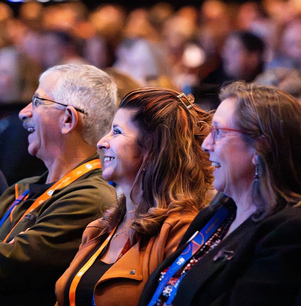 view of board members smiling in the audience as they listen to General Session speakers