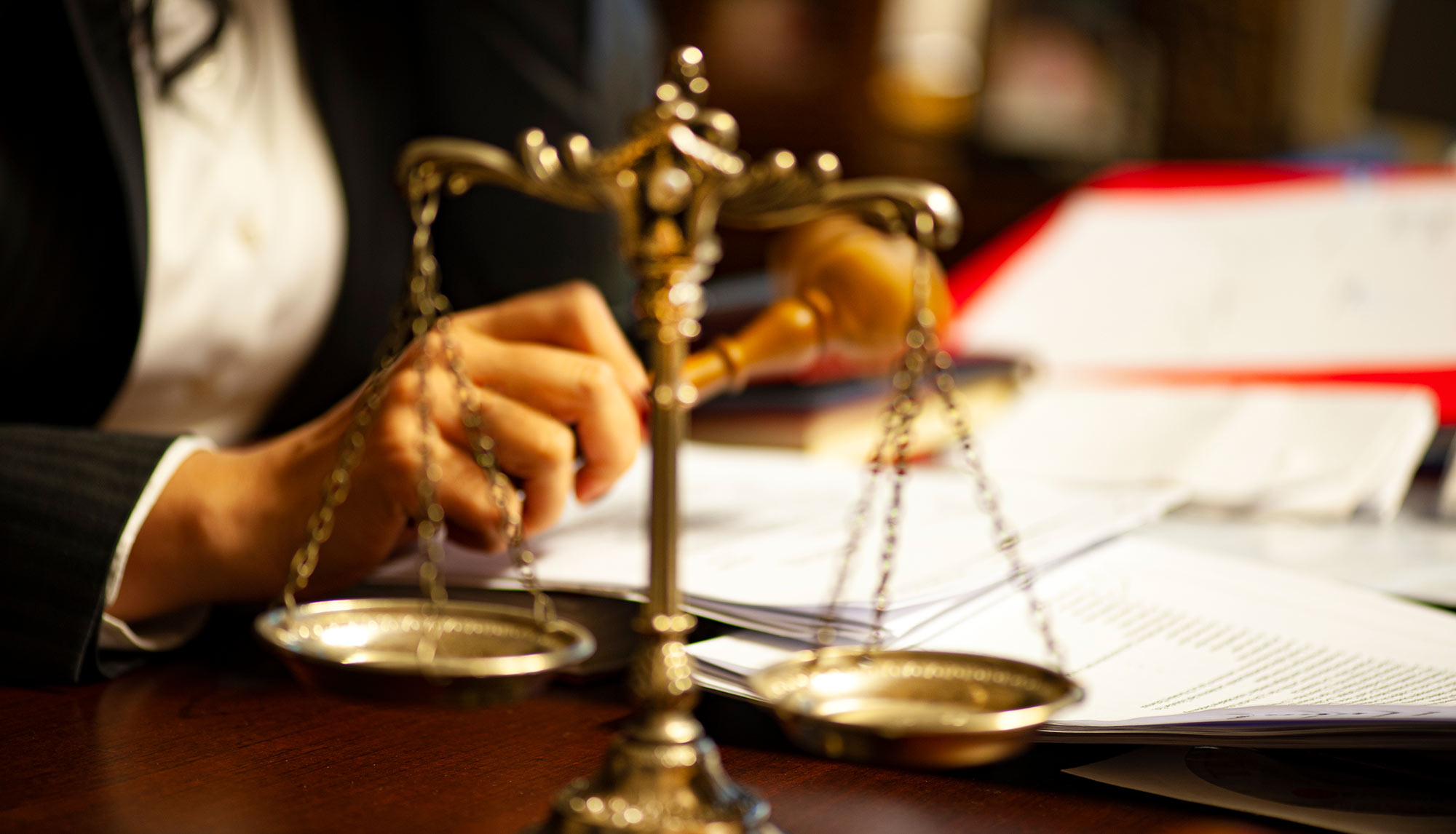Gold scale on a table with a person in the background working on the table with papers scattered around