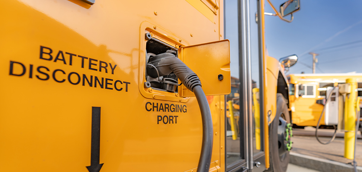 close up of a charging port with a plug connected on the side of a yellow school bus