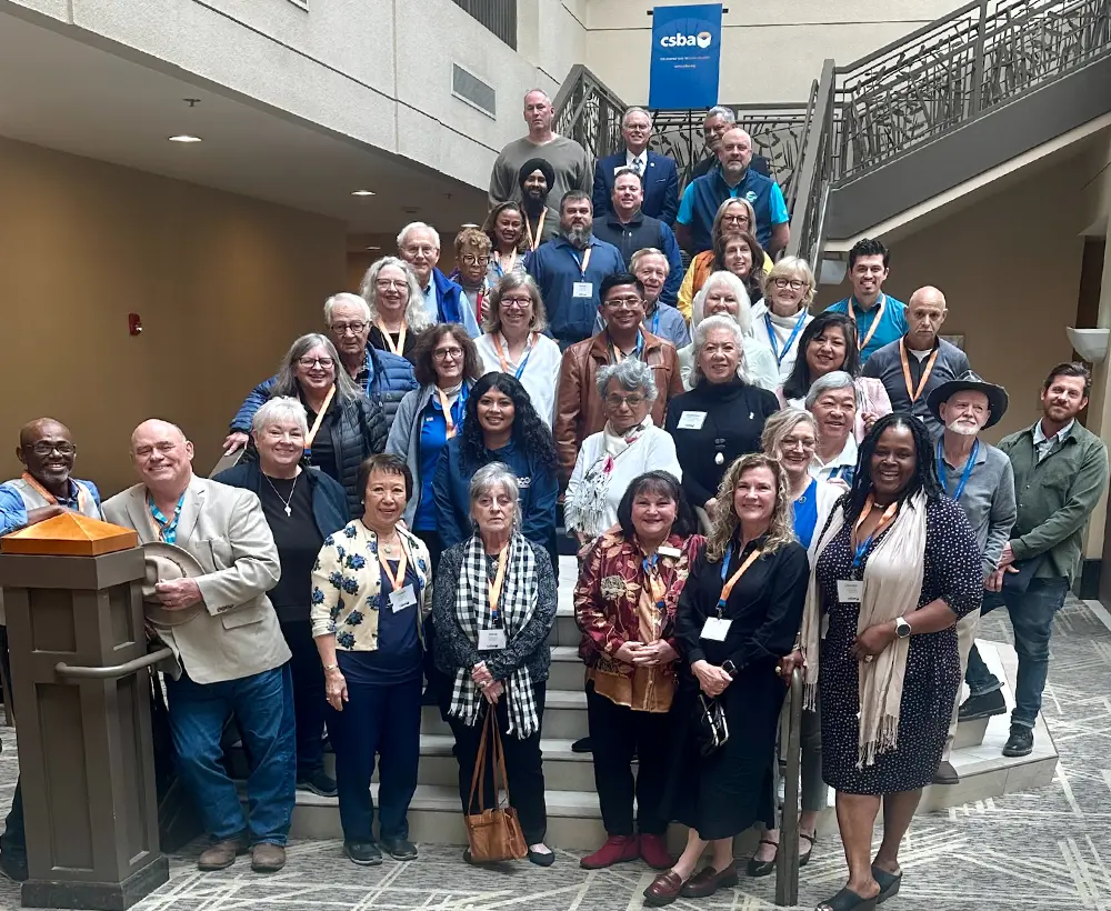 County Board members from across California take a large group photo on a foyer staircase during their Sacramento workshop