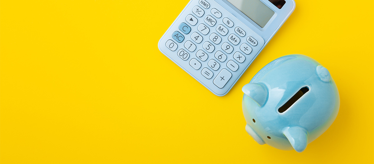 calculator and blue piggy bank in front of a yellow background