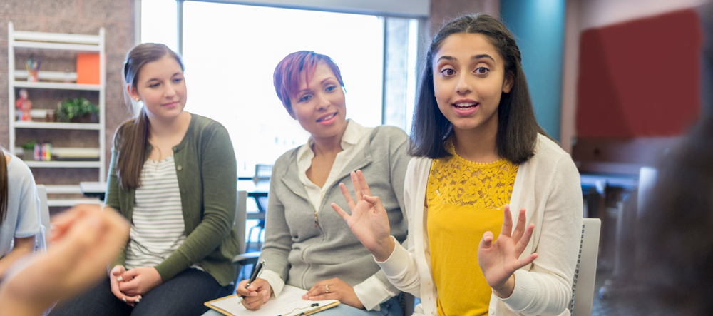 A group of young women seated in a circle, engaged in conversation