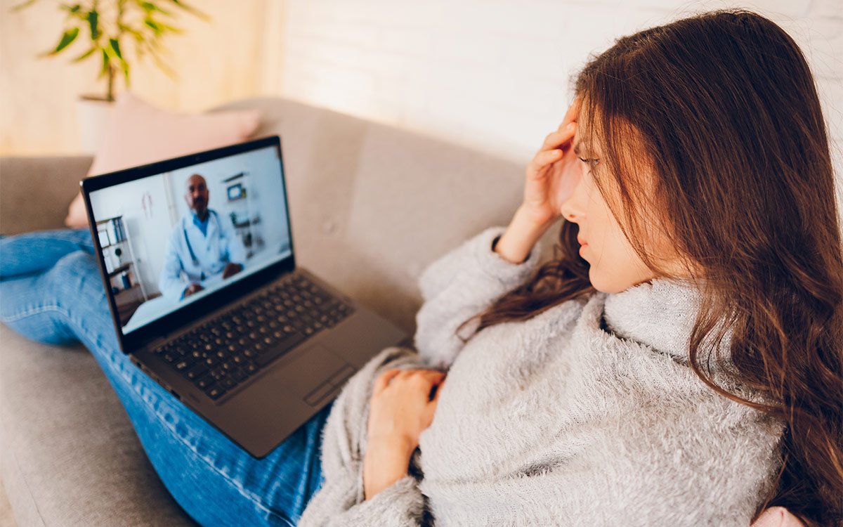 woman sitting on the couch with her feet up and watching a video from her laptop