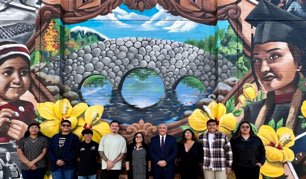 group photo of people standing in front of mural