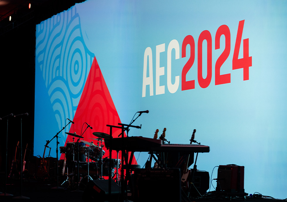 angled view of the AEC 2024 stage showing the conference brand graphic and logo