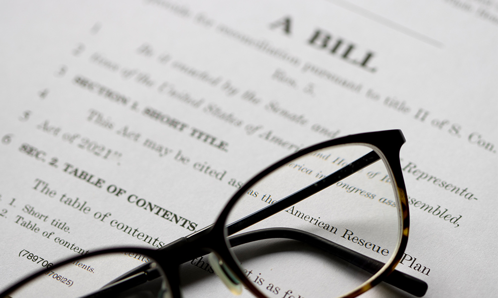 a pair of reading glasses sits on a packet of papers labelled A Bill