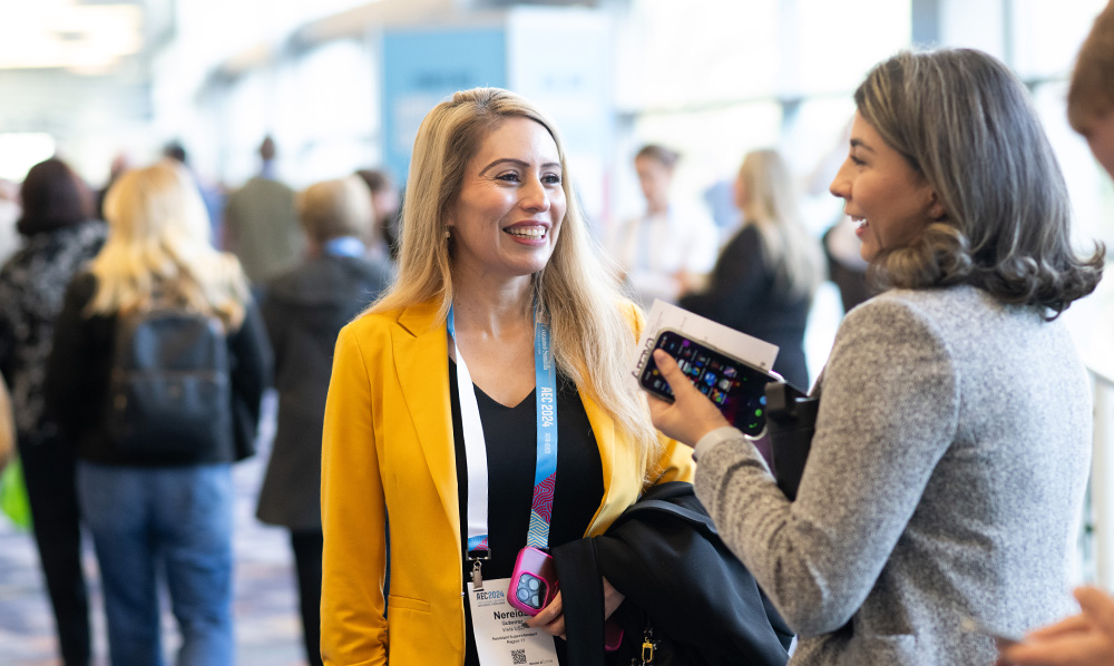 two women mingle at a busy indoor event