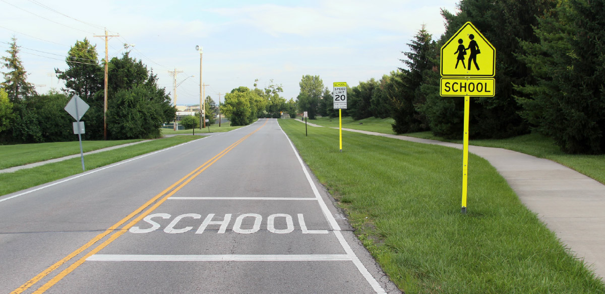 A school zone with pavement markings, a school crossing warning sign, and a reduced speed limit sign to ensure the safety of children.