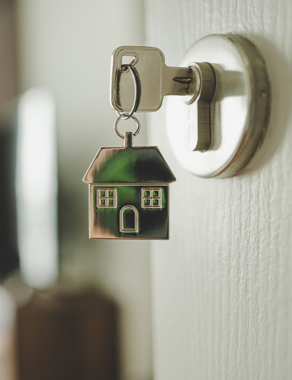 a house keychain hangs from a key in a door lock