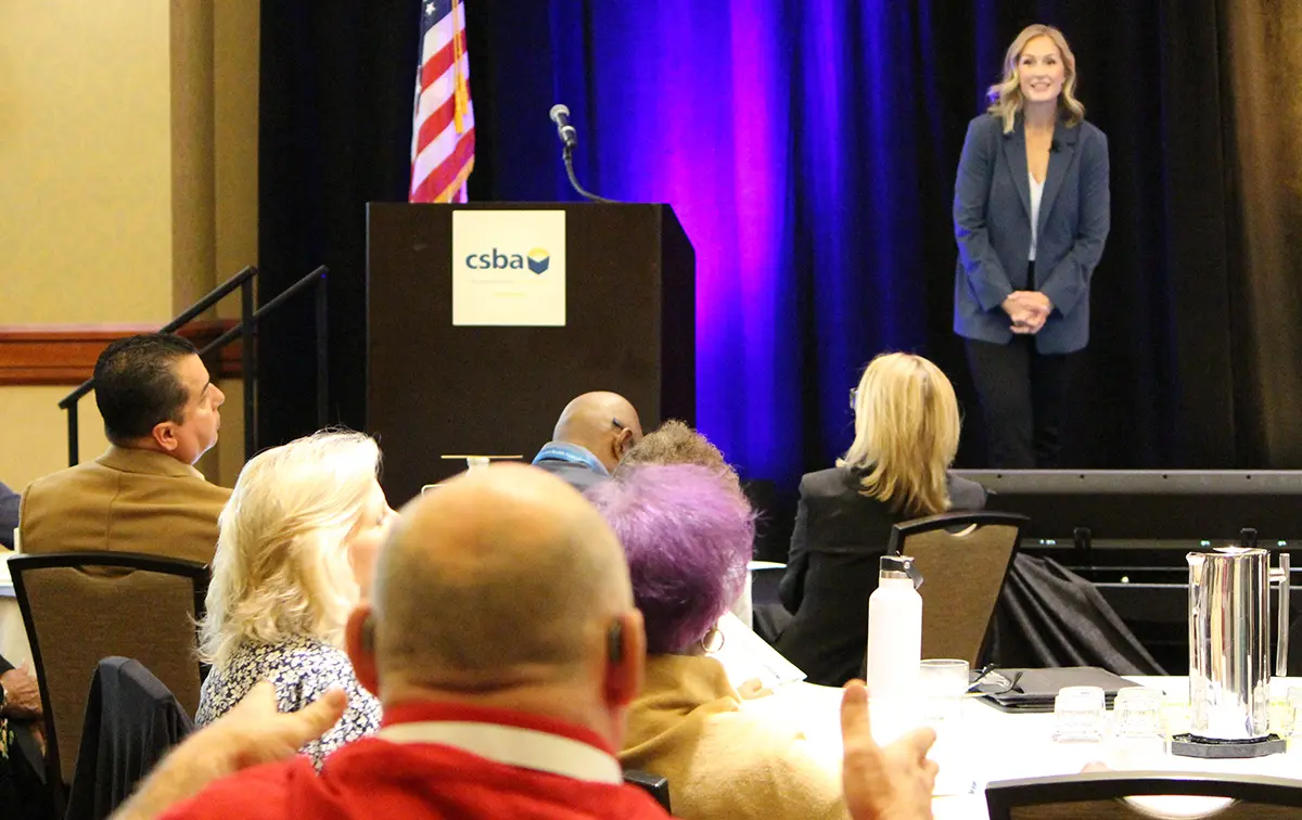 Erin Mahoney speaking on stage while attendees watch