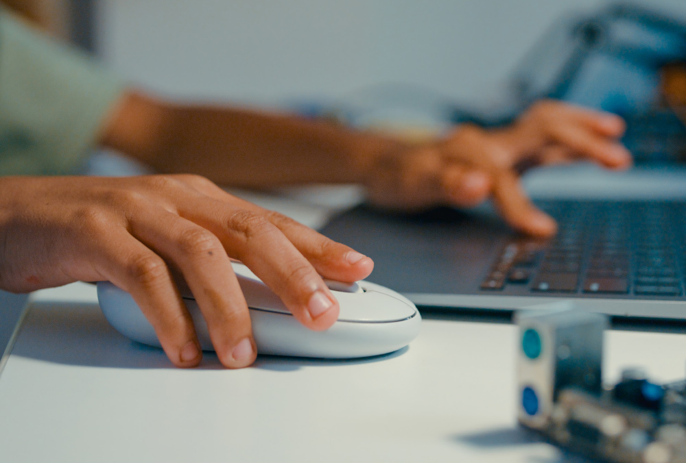 closeup of hands using a mouse and laptop
