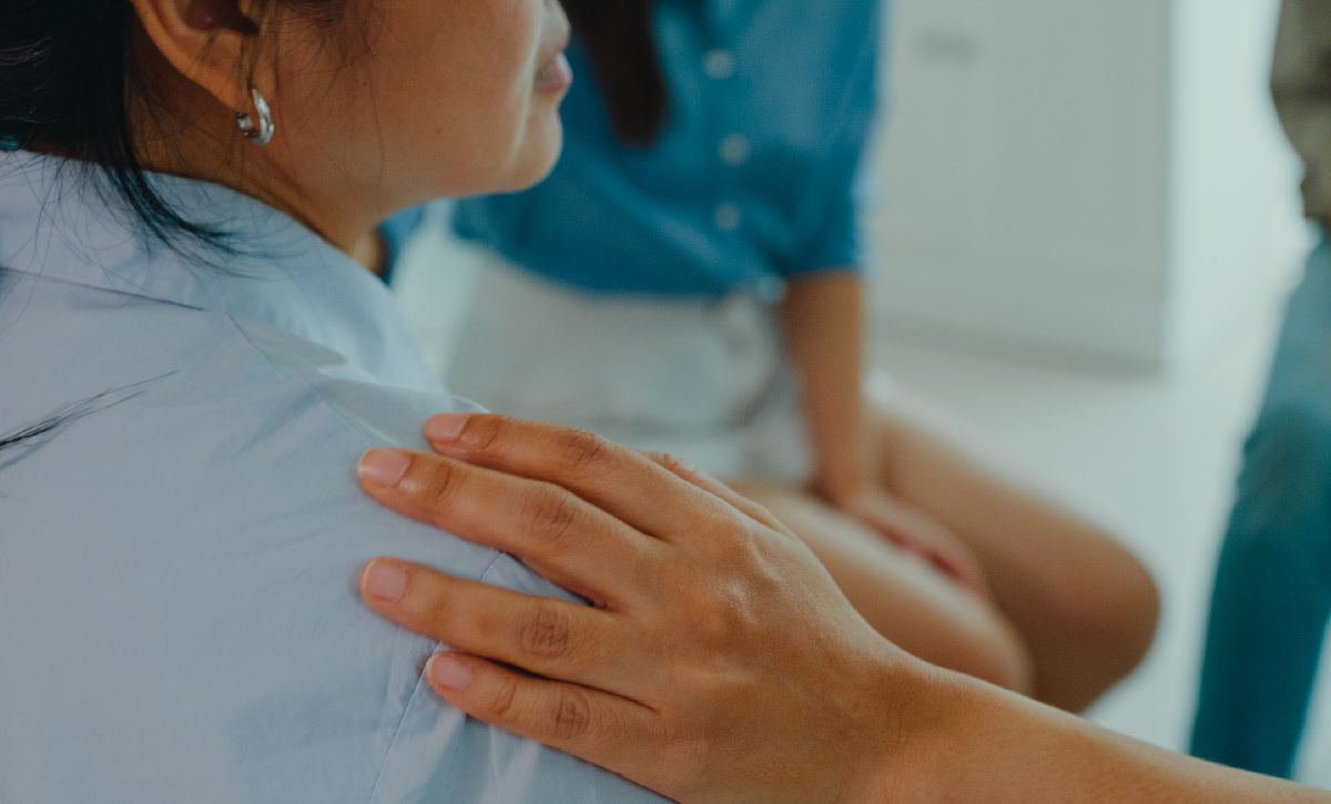 closeup of a person resting their hand on another person's shoulder 
