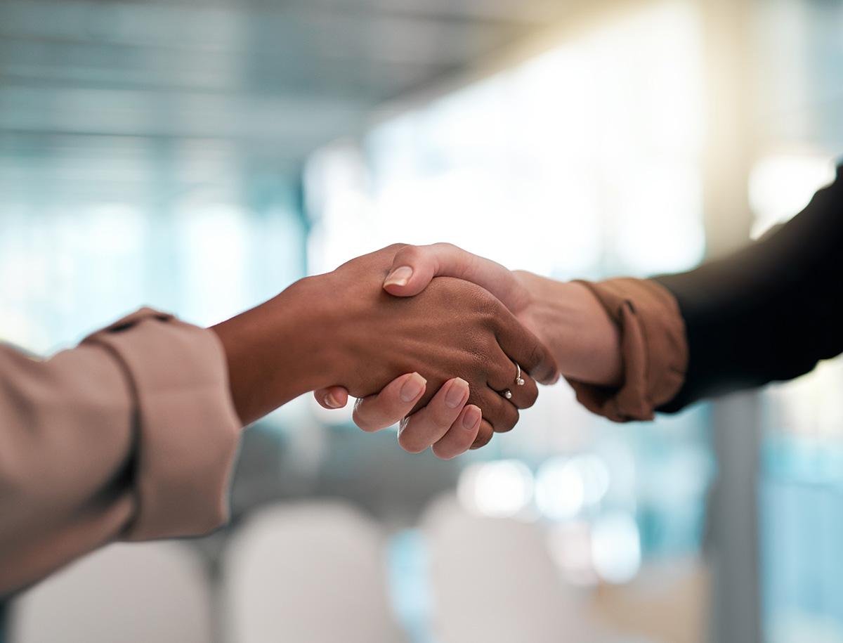 Two people with different skin tones shaking hands, symbolizing agreement, partnership, or collaboration.