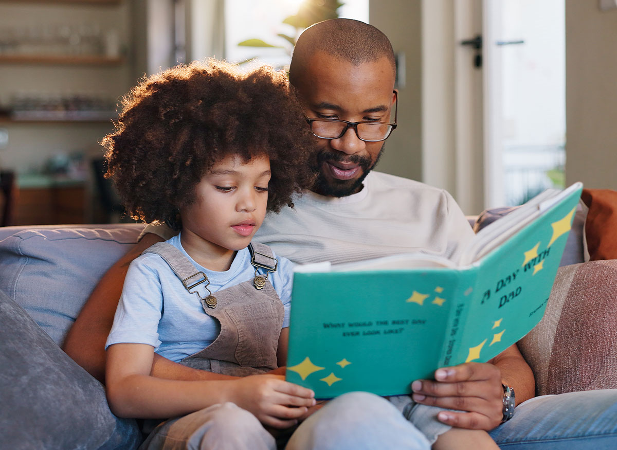 Dad reading a story to his young child on a sunny day at home