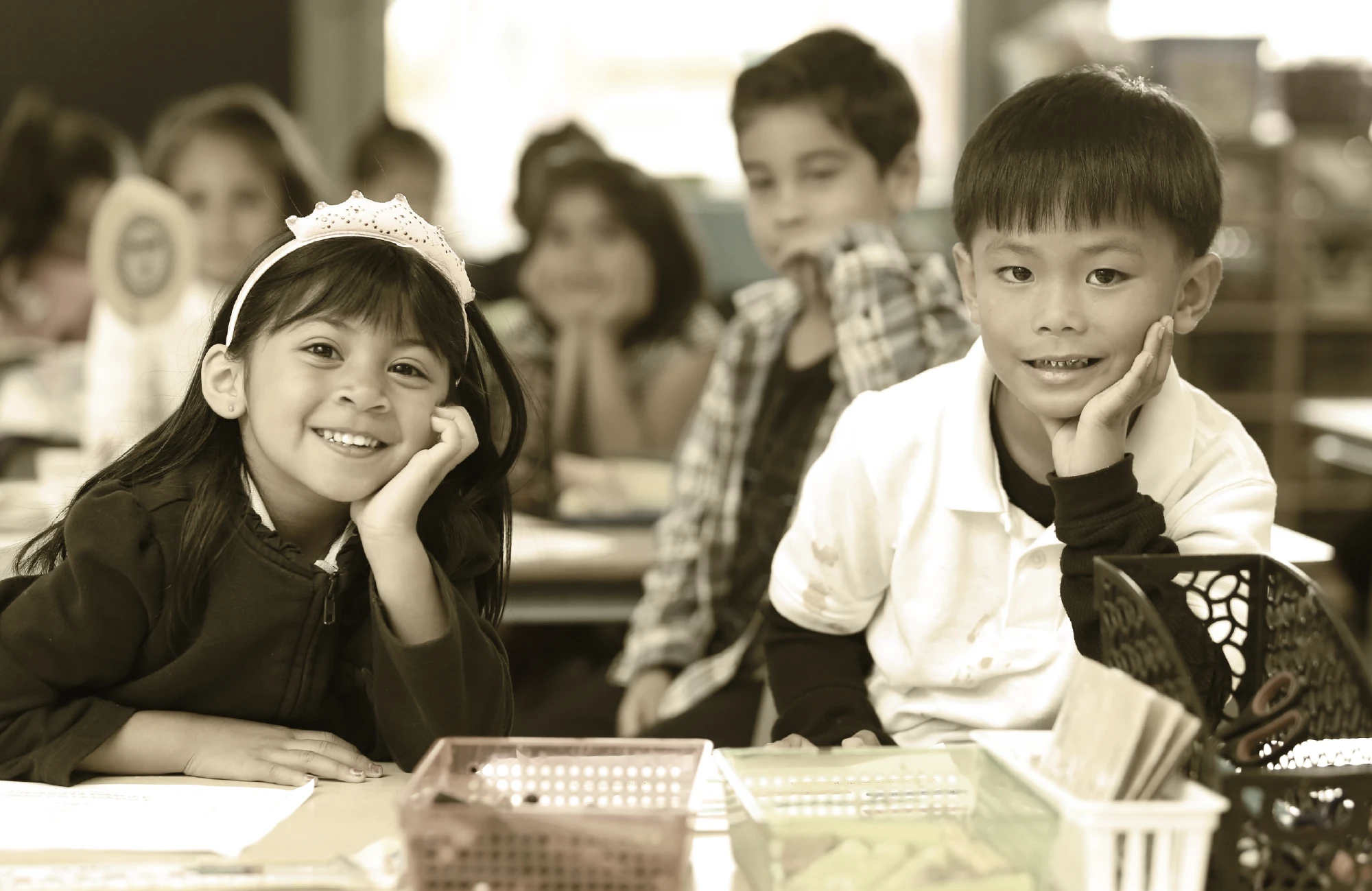 Smiling young elementary school students sitting at desks in a classroom.