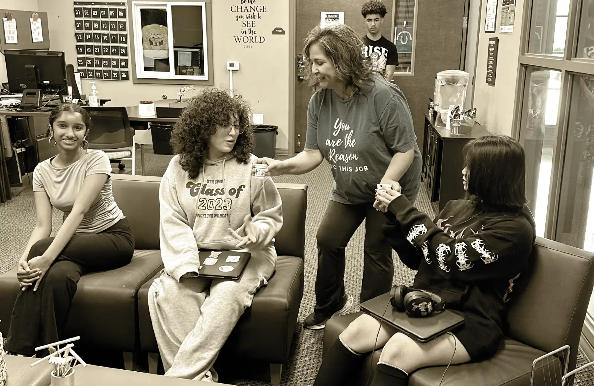 A female adult counselor interacting with three high school students seated on a couch in a resource center.