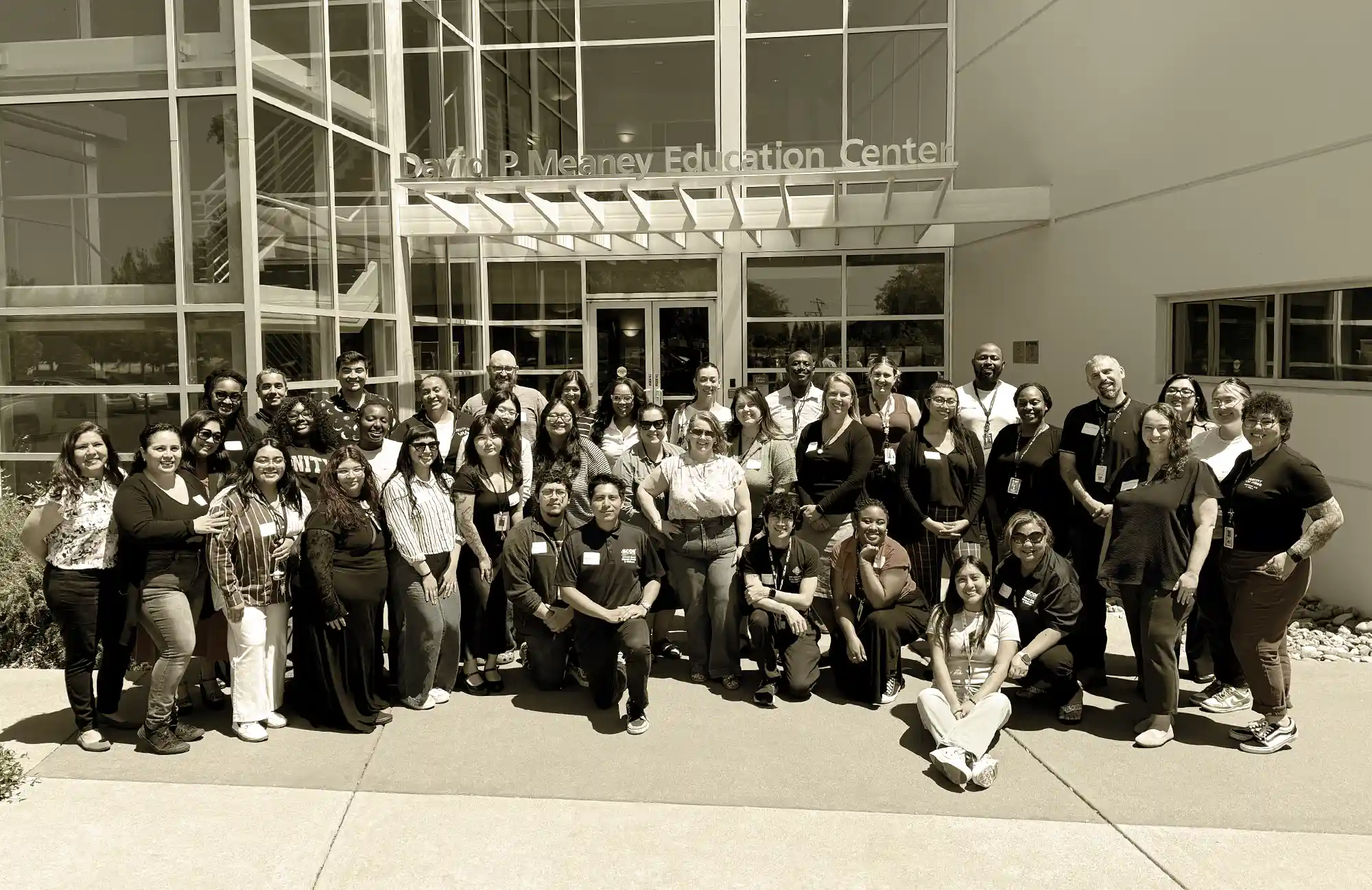 Diverse team of educators at a training or professional development event posing for a group picture outside a modern building.